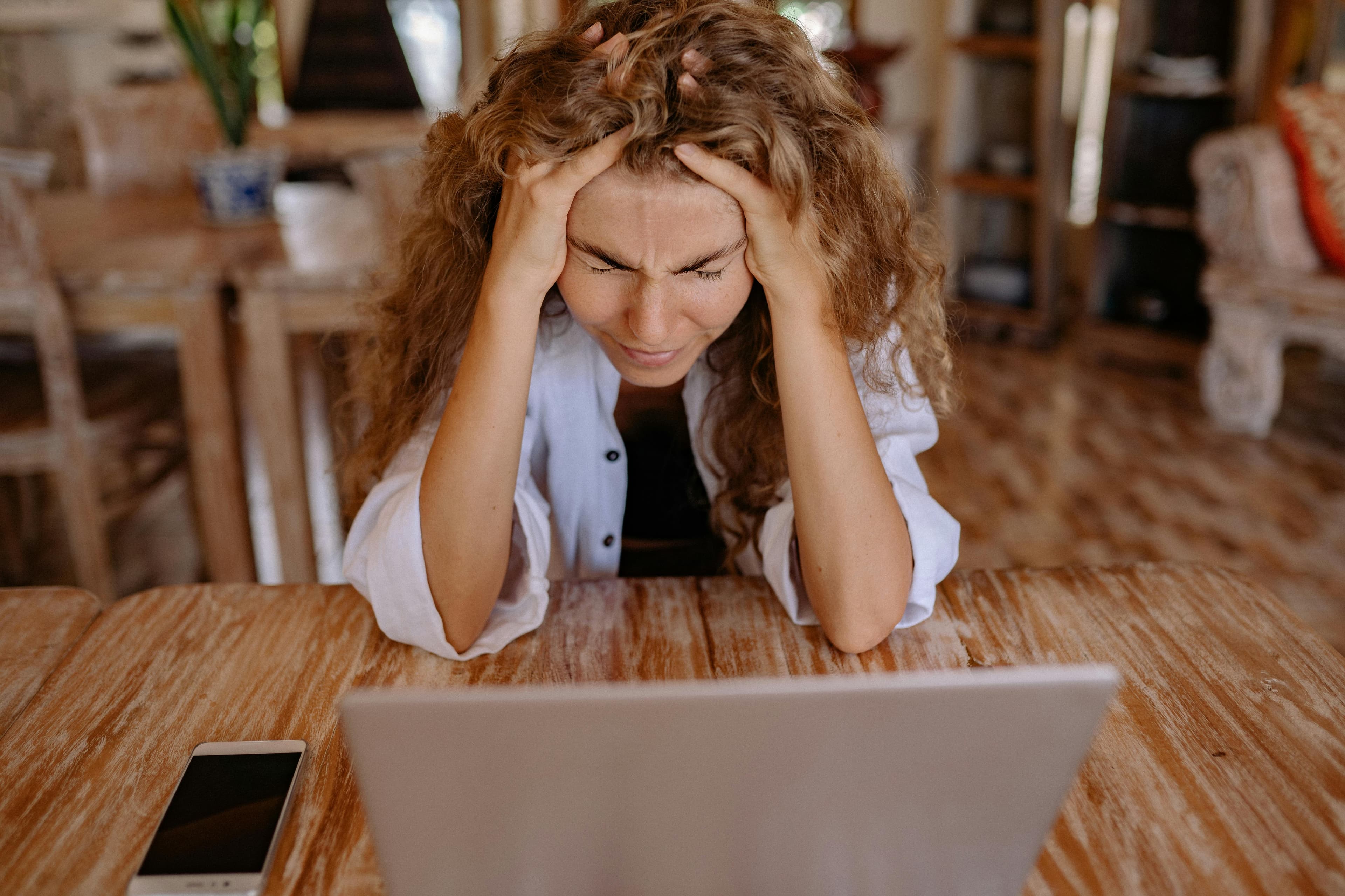 Frau mit Händen am Kopf vor einem Laptop — Finanzstress am Esstisch